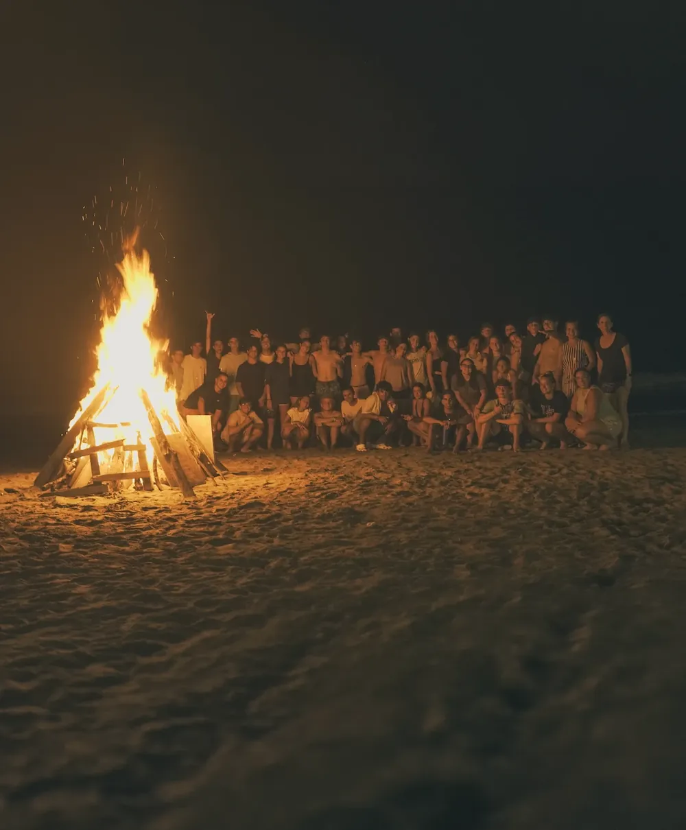 Grupo alrededor de una fogata en la playa de noche