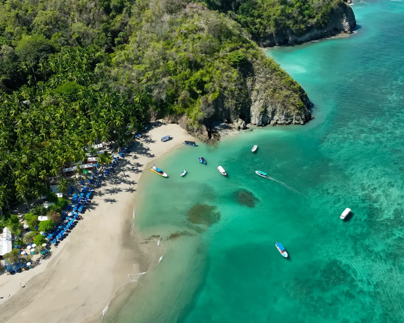 Playa de arena blanca y aguas turquesa con lanchas